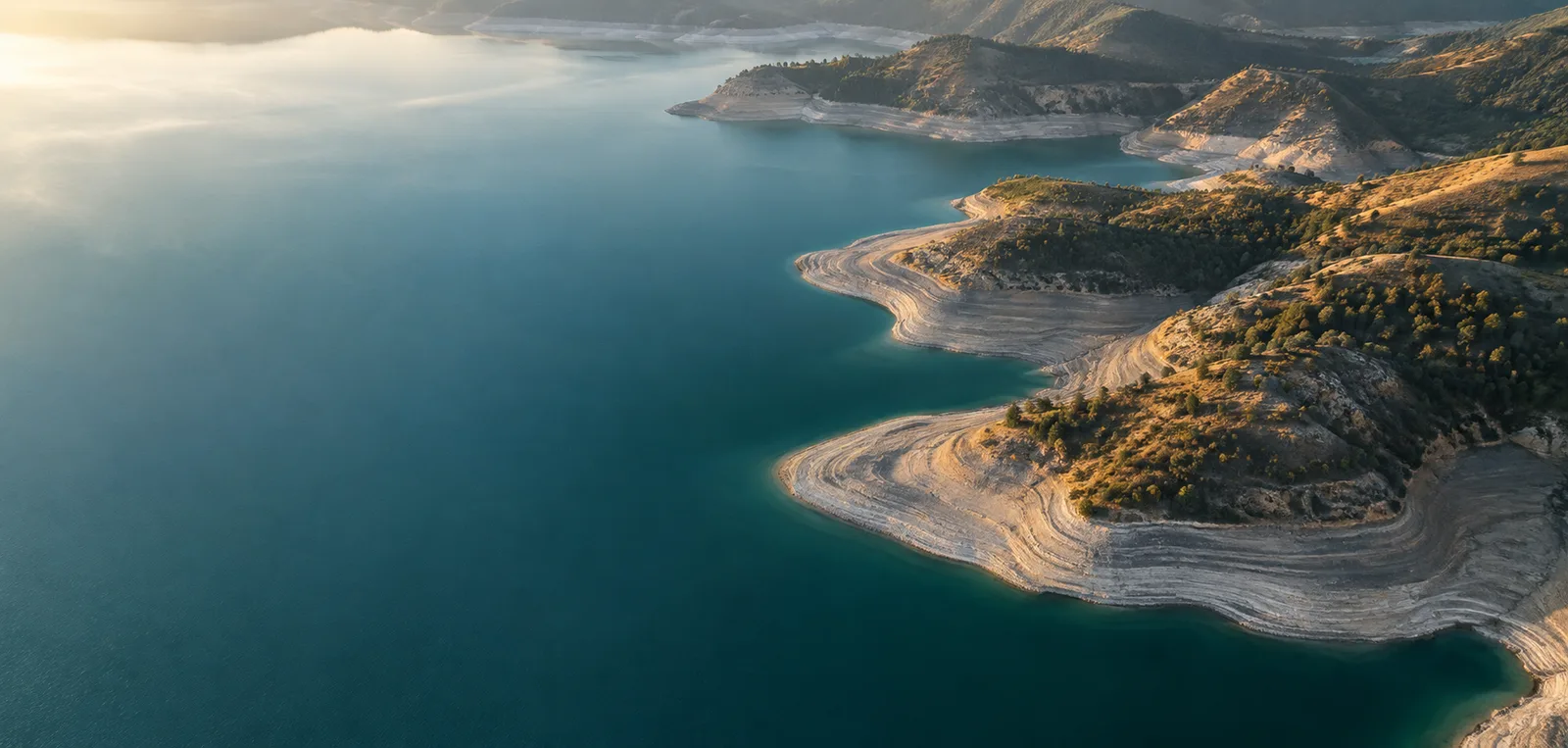 Illustrative aerial reservoir shoreline in morning light
