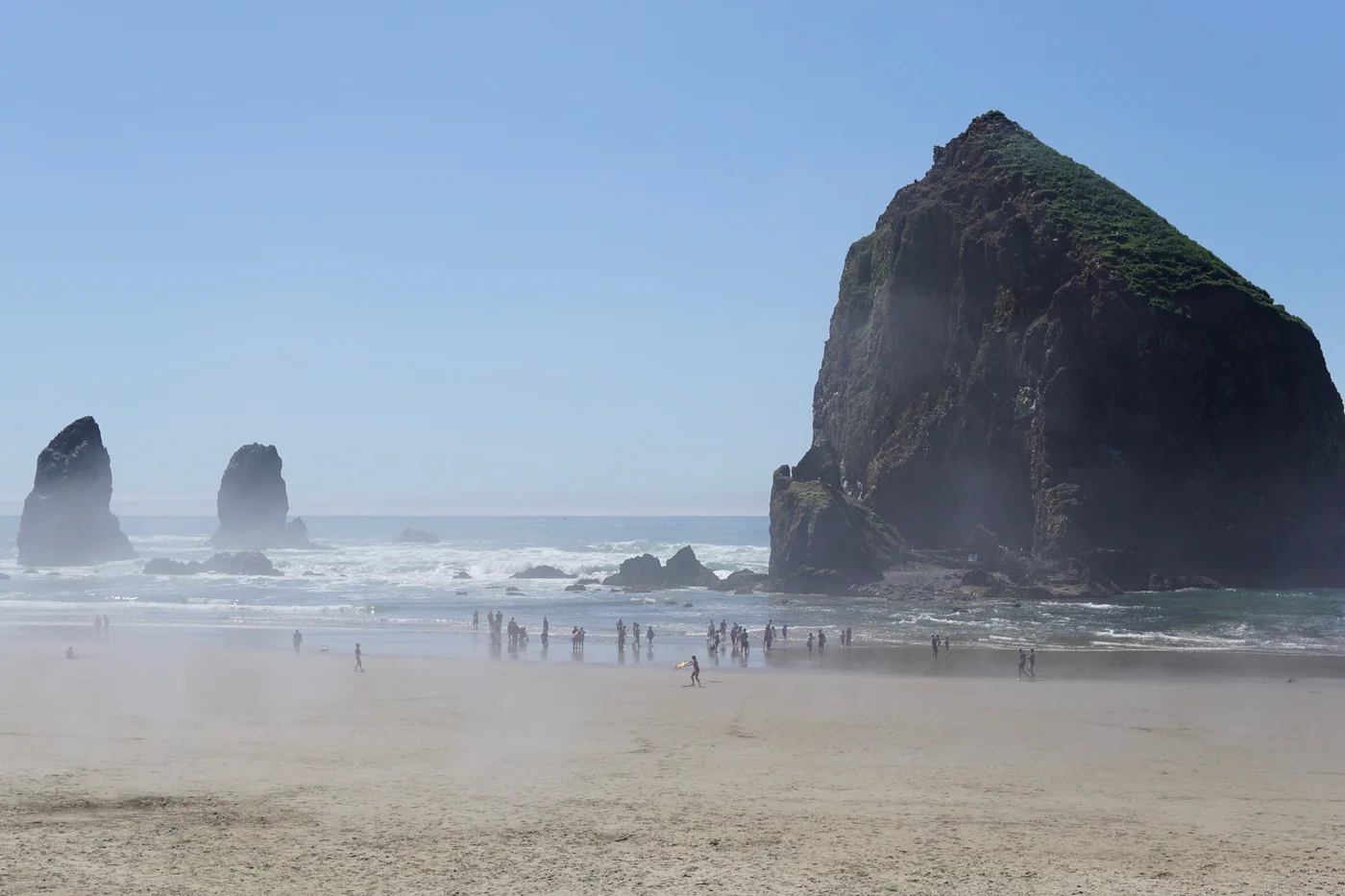 Haystack Rock and the Needles above a misty beach in Cannon Beach, Oregon.