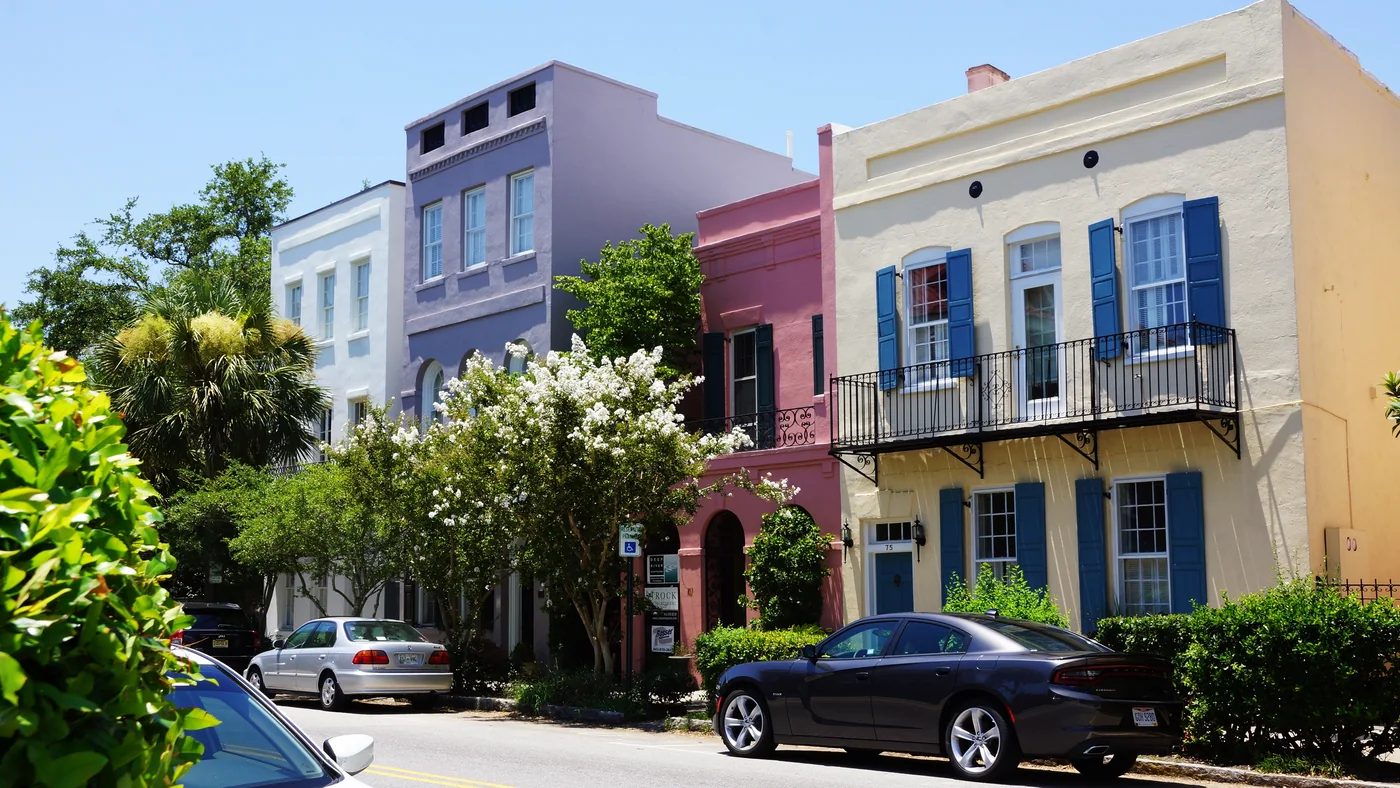 Real photograph of Rainbow Row in Charleston, South Carolina, with pastel townhouses and street trees.