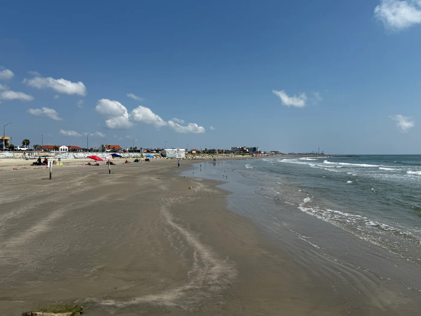 The sandy beach and Gulf surf in Galveston, Texas, viewed along the shoreline.